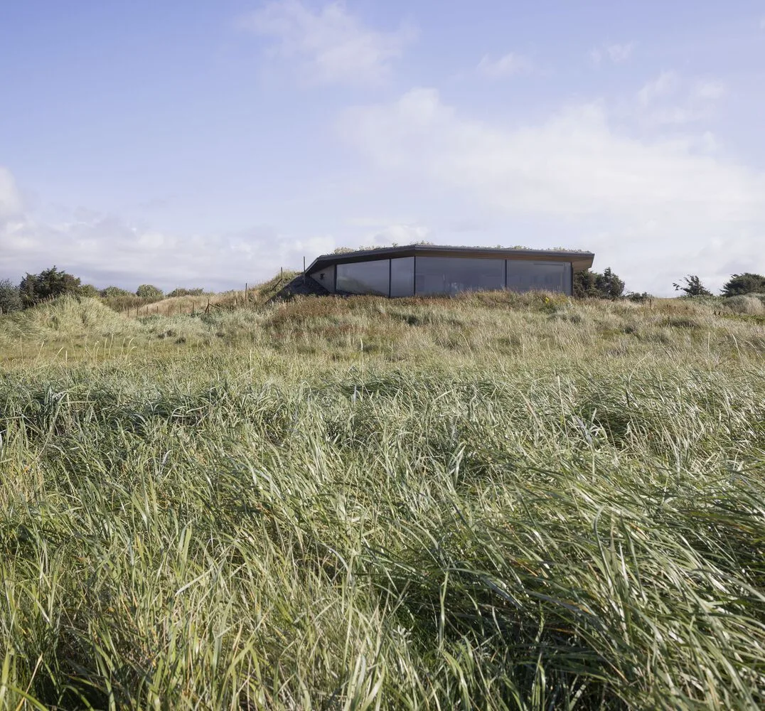A vacation home design that coexists with sand dunes and the sea, showcasing the natural poetic and expansive beauty of the Norwegian coast