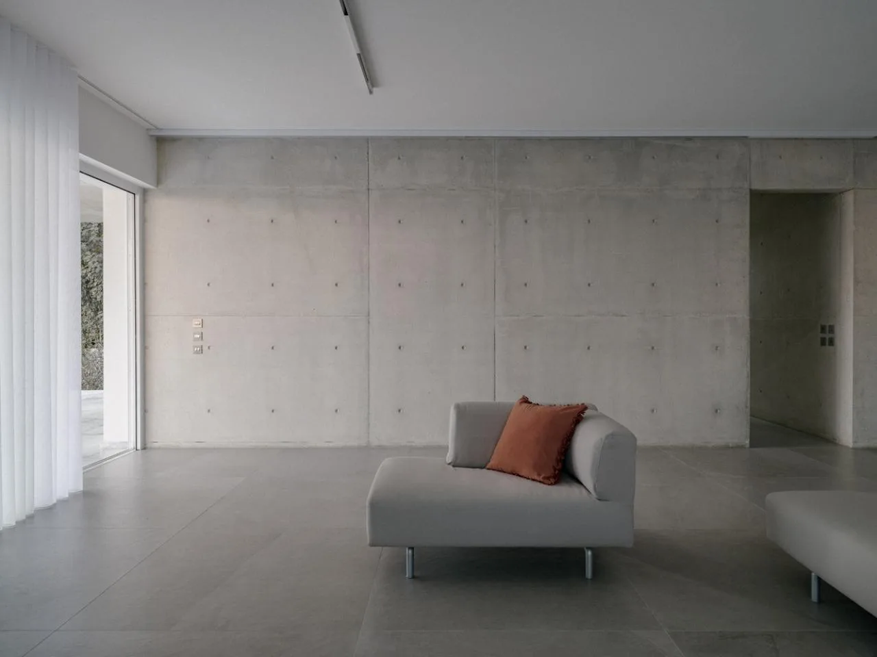 Sculpture like exposed concrete runs through the entire narrow rectangular flat design